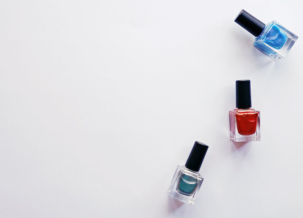 Three colorful nail polish bottles arranged creatively on a white backdrop, showcasing vibrant beauty products.